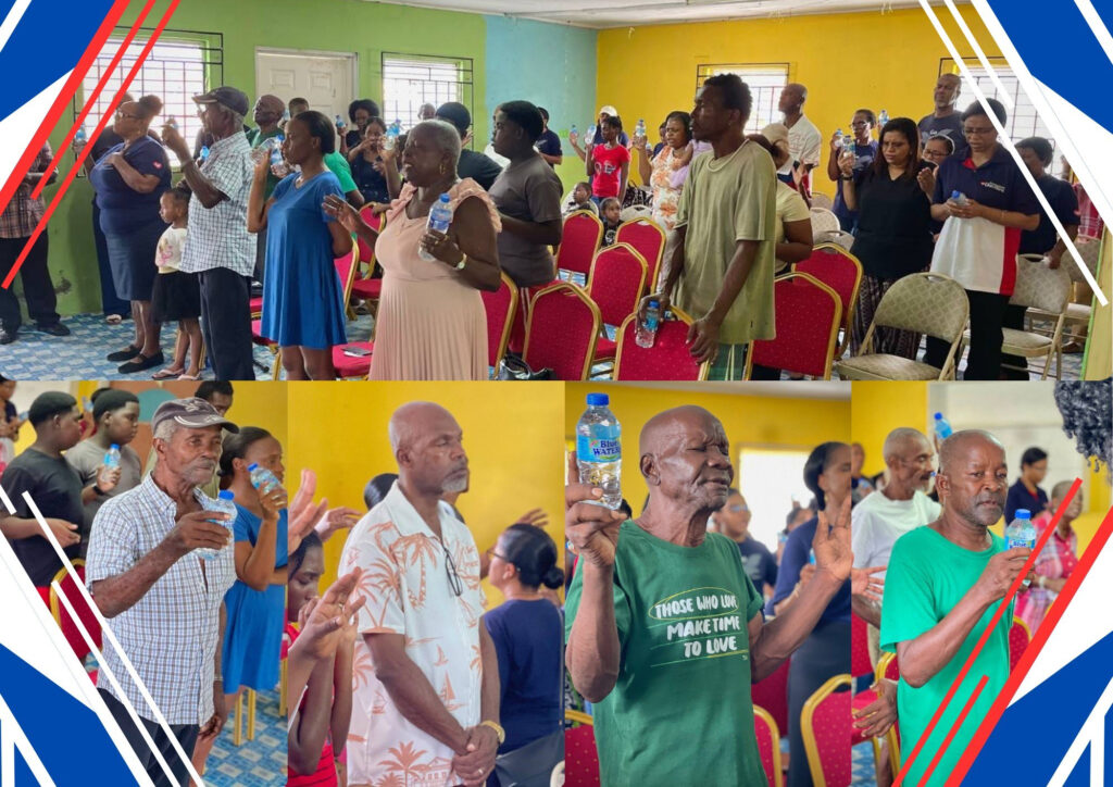 Residents of Dennery holding up bottles of water during a time of prayer and blessing with the Universal Church